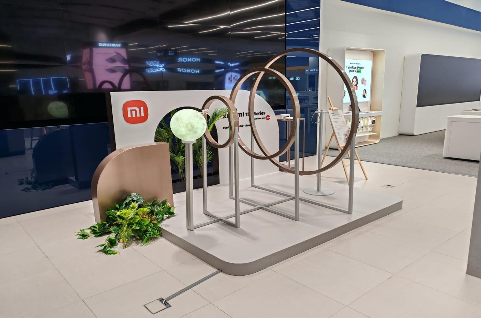 Promotional kiosk displaying products with a blue counter and digital screen showcasing bottled beverages, set in an elegant traditional setting.